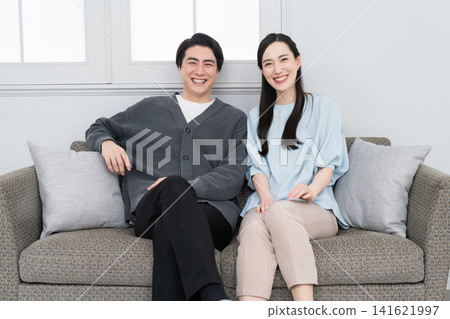 A young man and woman relaxing on a sofa: Lifestyle image A young man and woman relaxing on a sofa: Lifestyle image 141621997