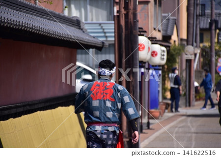 日本愛知縣犬山市：在犬山春季祭期間，一名身穿法被的男子走在街上，道路兩旁掛滿了燈籠。 141622516