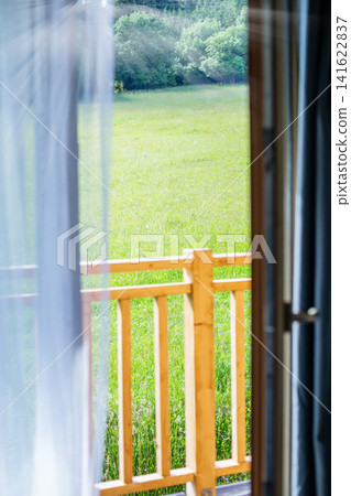 Sunny meadow view through open wooden door with copy space. Perfect background for text, travel, rustic villa, or summer holiday theme. Sunny meadow view through open wooden door with copy space. Perfect background for text, travel, rustic villa, or summer holiday theme. 141622837