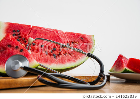 A conceptual photo showcasing a medical stethoscope with ripe red watermelon, symbolizing cardiovascular health, nutrition, and wellness. A conceptual photo showcasing a medical stethoscope with ripe red watermelon, symbolizing cardiovascular health, nutrition, and wellness. 141622839