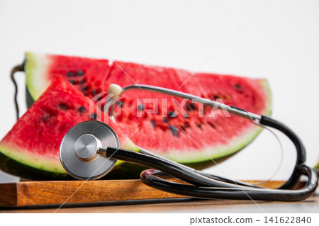 A conceptual photo showcasing a medical stethoscope with ripe red watermelon, symbolizing cardiovascular health, nutrition, and wellness. A conceptual photo showcasing a medical stethoscope with ripe red watermelon, symbolizing cardiovascular health, nutrition, and wellness. 141622840