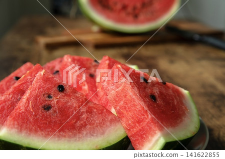 Juicy slices of ripe red watermelon with black seeds close up on a rustic wooden table. perfect summer refreshing fruit food dessert. 141622855