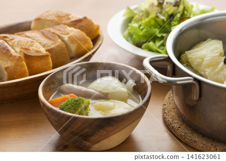 A steaming hot pot-au-feu served in a wooden bowl, accompanied by baguette slices. A steaming hot pot-au-feu served in a wooden bowl, accompanied by baguette slices. 141623061