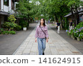 一位女士漫步在東京一處復古旅遊景點（深大寺附近的一條公共道路）。 141624915