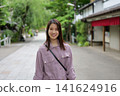 一位女士漫步在東京一處復古旅遊景點（深大寺附近的一條公共道路）的肖像。 141624916