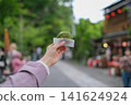 一位女士在東京一處復古旅遊景點（深大寺附近的一條公共道路）邊走邊吃包子的特寫鏡頭。 141624924