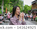 一位女士在東京一處復古旅遊景點（深大寺附近的一條公共道路）吃街頭小吃。 141624925