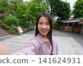 一位微笑的女子在東京一處復古旅遊景點（深大寺附近的一條公共道路）自拍。 141624931