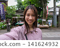一位微笑的女子在東京一處復古旅遊景點（深大寺附近的一條公共道路）自拍。 141624932