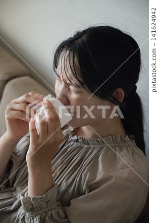 Young woman suffering from hay fever and sneezing Young woman suffering from hay fever and sneezing 141624942