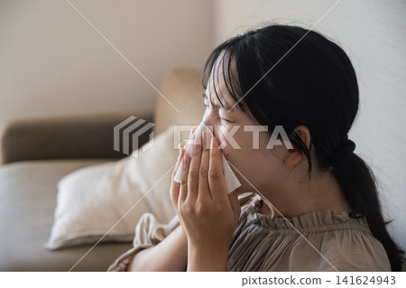 Young woman suffering from hay fever and sneezing Young woman suffering from hay fever and sneezing 141624943