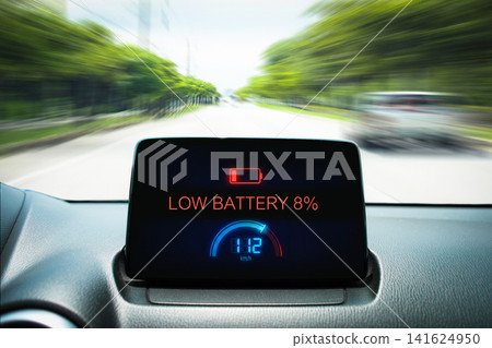 Dashboard display of an electric vehicle showing a low battery warning sign Dashboard display of an electric vehicle showing a low battery warning sign 141624950