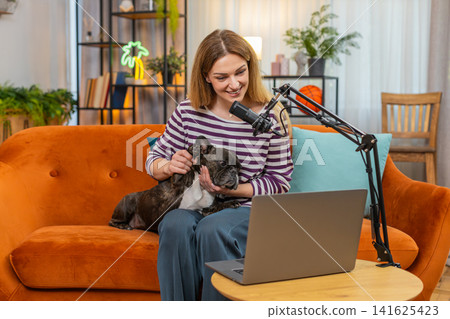 Middle-aged woman with dog uses studio microphone and starts live podcast about pet care series Middle-aged woman with dog uses studio microphone and starts live podcast about pet care series 141625423
