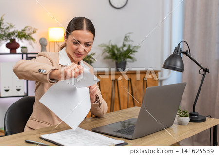 Young businesswoman rips error draft report opens new document and starts fast typing on laptop fast Young businesswoman rips error draft report opens new document and starts fast typing on laptop fast 141625539