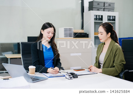 Asian businesswoman signs a car loan contract, receives the vehicle key, and shakes hands with a finance agent. Ideal for commercial auto insurance Asian businesswoman signs a car loan contract, receives the vehicle key, and shakes hands with a finance agent. Ideal for commercial auto insurance 141625884