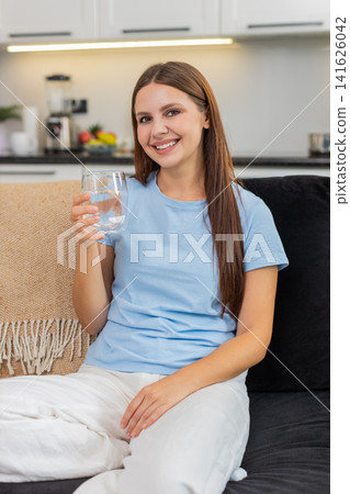 Young woman drinks water from glass keeps hydration good habit healthy lifestyle uses filter system Young woman drinks water from glass keeps hydration good habit healthy lifestyle uses filter system 141626042