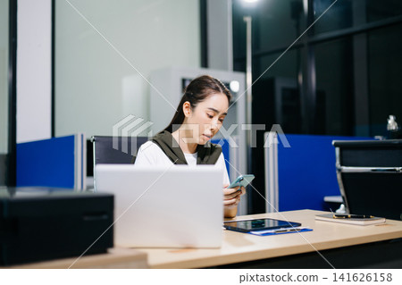 Asian woman feeling migraine head strain.Overworked businesswoman financier while working on laptop and tablet at office. Asian woman feeling migraine head strain.Overworked businesswoman financier while working on laptop and tablet at office. 141626158