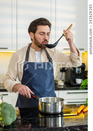Middle-aged man seasoning homemade healthy soup on electric stove in home kitchen for hot diet meal Middle-aged man seasoning homemade healthy soup on electric stove in home kitchen for hot diet meal 141626165