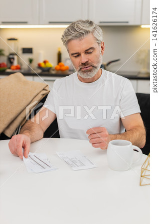 Middle-aged man builds budget on laptop organizes invoices adds expenses and income sets priorities Middle-aged man builds budget on laptop organizes invoices adds expenses and income sets priorities 141626174