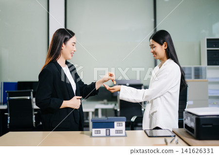 Real estate agent handing over house keys to a new homeowner, symbolizing property ownership transfer, successful home purchase and investment Real estate agent handing over house keys to a new homeowner, symbolizing property ownership transfer, successful home purchase and investment 141626331