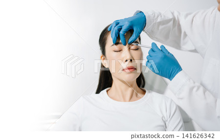 Doctor consulting patient in beauty clinic, skincare analysis, aesthetic treatment planning, professional advice, clean medical setting, modern cosmetic care for healthy skin. 141626342