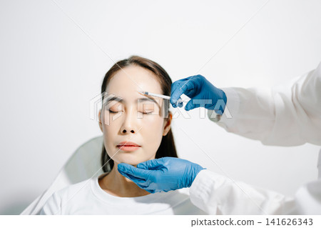 Doctor consulting patient in beauty clinic, skincare analysis, aesthetic treatment planning, professional advice, clean medical setting, modern cosmetic care for healthy skin. Doctor consulting patient in beauty clinic, skincare analysis, aesthetic treatment planning, professional advice, clean medical setting, modern cosmetic care for healthy skin. 141626343