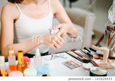 Asian woman carefully applies lipstick in front of a vanity mirror, highlighting her daily beauty and makeup routine. Asian woman carefully applies lipstick in front of a vanity mirror, highlighting her daily beauty and makeup routine. 141626433