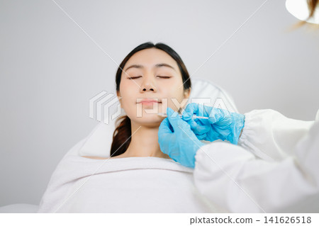 Doctor consulting patient in beauty clinic with facial analysis and skincare planning. Professional aesthetic treatment, clean sterile care, modern dermatology for radiant skin. Doctor consulting patient in beauty clinic with facial analysis and skincare planning. Professional aesthetic treatment, clean sterile care, modern dermatology for radiant skin. 141626518