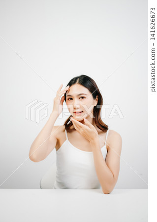 Asian woman with radiant skin posing in a clean white studio. Natural beauty, skincare, wellness and self-care concept with copy space for branding. Asian woman with radiant skin posing in a clean white studio. Natural beauty, skincare, wellness and self-care concept with copy space for branding. 141626673