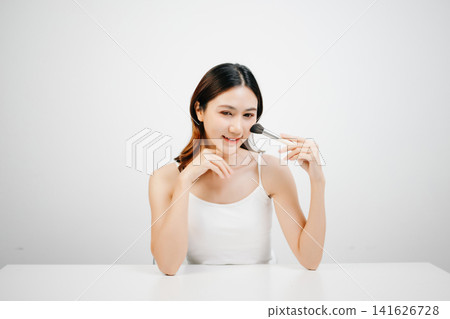Asian woman holding lipstick with clean minimal style, soft light and natural beauty look for cosmetic advertising Asian woman holding lipstick with clean minimal style, soft light and natural beauty look for cosmetic advertising 141626728