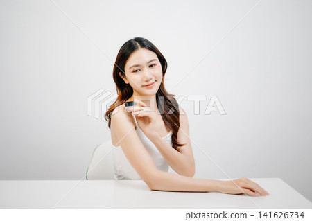 Asian woman presenting skincare product with clean minimal aesthetic, glowing skin and beauty routine concept for cosmetic advertising Asian woman presenting skincare product with clean minimal aesthetic, glowing skin and beauty routine concept for cosmetic advertising 141626734