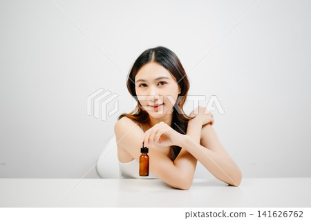 Asian woman holding serum with clean minimal aesthetic, glowing skin and skincare routine concept for cosmetic advertising, branding and product promotion Asian woman holding serum with clean minimal aesthetic, glowing skin and skincare routine concept for cosmetic advertising, branding and product promotion 141626762
