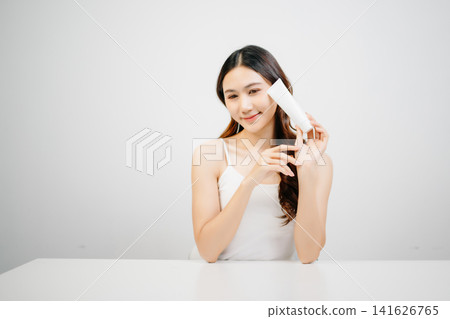 Asian woman presenting skincare product with clean minimal aesthetic, glowing skin and beauty routine concept for cosmetic advertising Asian woman presenting skincare product with clean minimal aesthetic, glowing skin and beauty routine concept for cosmetic advertising 141626765
