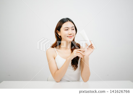 Asian woman presenting skincare product with clean minimal aesthetic, glowing skin and beauty routine concept for cosmetic advertising Asian woman presenting skincare product with clean minimal aesthetic, glowing skin and beauty routine concept for cosmetic advertising 141626766