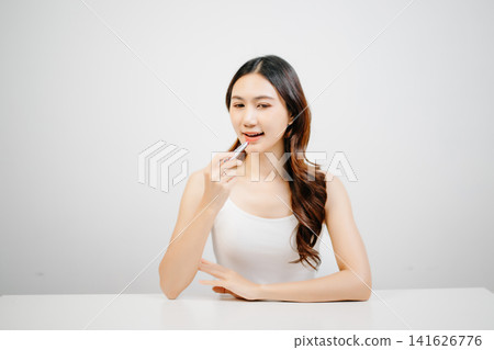 Asian woman holding lipstick with clean minimal style, soft light and natural beauty look for cosmetic advertising, makeup promotion Asian woman holding lipstick with clean minimal style, soft light and natural beauty look for cosmetic advertising, makeup promotion 141626776
