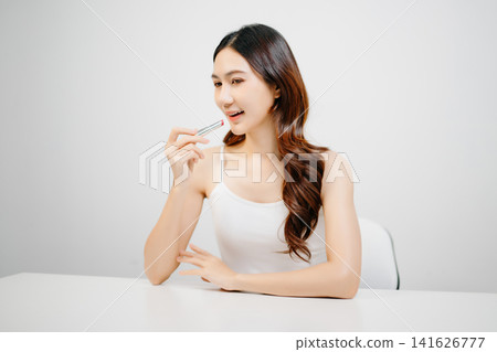 Asian woman holding lipstick with clean minimal style, soft light and natural beauty look for cosmetic advertising, makeup promotion Asian woman holding lipstick with clean minimal style, soft light and natural beauty look for cosmetic advertising, makeup promotion 141626777