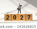 Miniature Man Lifting Dumbbells on Wooden 2027 Blocks Fitness and New Year Concept 141626815