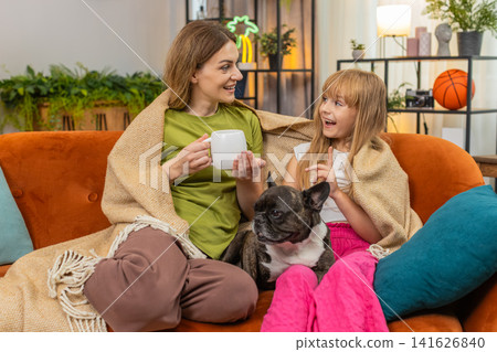 Mother daughter dog share tea and blanket relax together cozy rest hug smile comfort family evening Mother daughter dog share tea and blanket relax together cozy rest hug smile comfort family evening 141626840