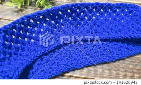 A blue thread pattern on a wooden background. Knitting tutorial and sample of the finished piece. A blue thread pattern on a wooden background. Knitting tutorial and sample of the finished piece. 141626942