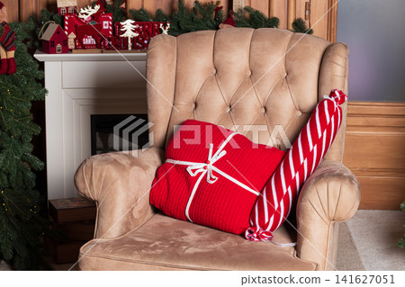 Cozy armchair with festive Christmas presents and decorations by the fireplace Cozy armchair with festive Christmas presents and decorations by the fireplace 141627051