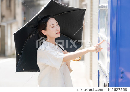 A woman buying a drink from a vending machine on a hot day. A woman buying a drink from a vending machine on a hot day. 141627268
