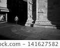 Lone Pedestrian in Dramatic Urban Light and Shadow 141627582