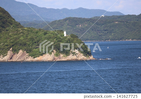 A landscape of the blue ocean, a peninsula with a lighthouse, mountain ranges, and sky. A landscape of the blue ocean, a peninsula with a lighthouse, mountain ranges, and sky. 141627725