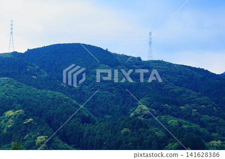 A landscape featuring power transmission towers and mountains covered in fresh greenery. A landscape featuring power transmission towers and mountains covered in fresh greenery. 141628386