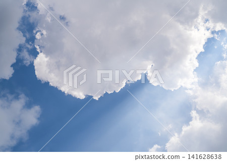 A photo of a blue sky with large white clouds, the edges of which shine through direct bright sunlight. Beautiful natural phenomena A photo of a blue sky with large white clouds, the edges of which shine through direct bright sunlight. Beautiful natural phenomena 141628638