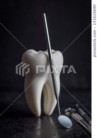 Dental Tooth Model With Stainless Steel Dental Tools and Mirror on Dark Background for Dentistry Dental Tooth Model With Stainless Steel Dental Tools and Mirror on Dark Background for Dentistry 141628890