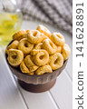 Bowl of Savory Taralli Ring Snacks on White Table with Olive Oil and Rustic Cloth 141628891