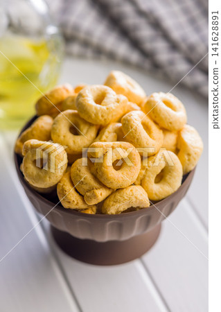 Bowl of Savory Taralli Ring Snacks on White Table with Olive Oil and Rustic Cloth 141628891