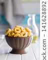 Bowl of Savory Taralli Ring Snacks on White Table with Olive Oil and Rustic Cloth 141628892