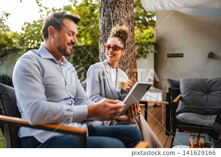 Couple discussing business outdoors using digital tablet Couple discussing business outdoors using digital tablet 141629166